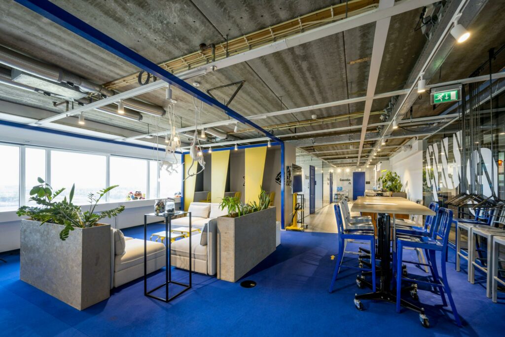 Modern kantoorinterieur aan de Johan Huizingalaan met blauwe vloer, open zitgedeelte, werkplekken en industriële plafondafwerking.